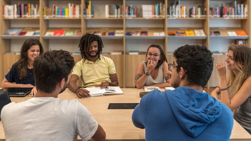Students sitting around the table in a library and chatting
