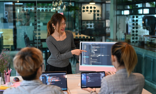 Data analyst pointing at a computer screen with graphs and dashboards